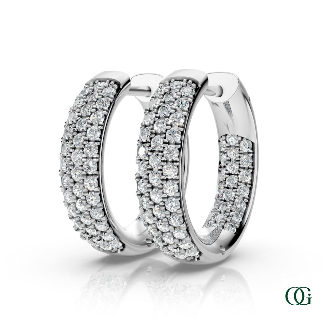 W | A pair of white gold inside-out hoop earrings paved with round diamonds, displayed on a clean white background with a soft reflection below. 