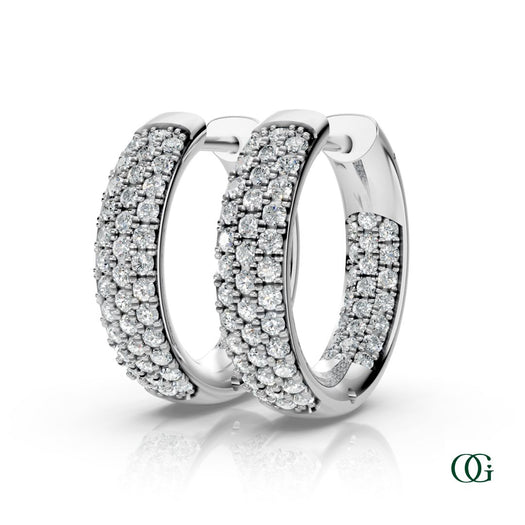 W | A pair of white gold inside-out hoop earrings paved with round diamonds, displayed on a clean white background with a soft reflection below. 