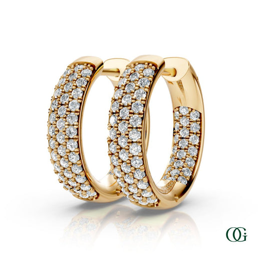 Y | A pair of yellow gold inside-out hoop earrings paved with round diamonds, displayed on a clean white background with a soft reflection below. 