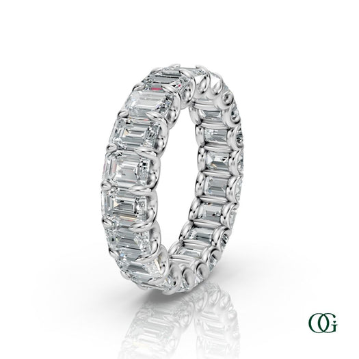 W | A White gold eternity ring featuring a continuous row of emerald-cut clear diamonds, set against a clean white background with a soft reflection below.