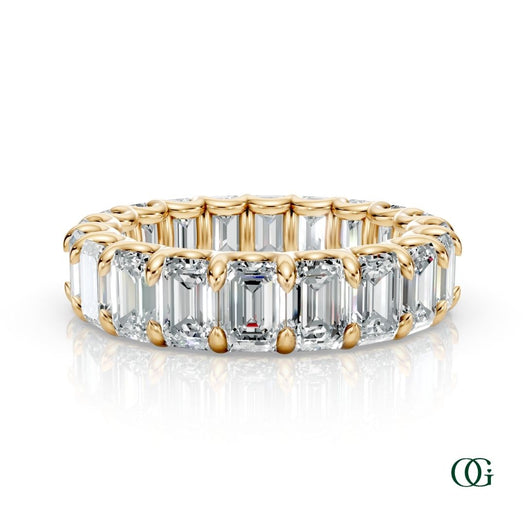 Y | A yellow gold eternity ring featuring a continuous row of emerald-cut clear diamonds, set against a clean white background with a soft reflection below.