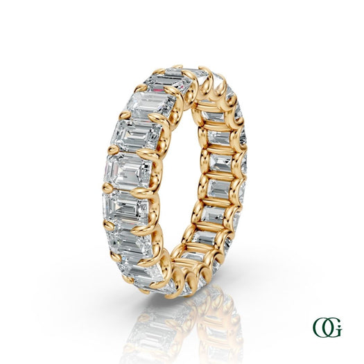 Y | A yellow gold eternity ring featuring a continuous row of emerald-cut clear diamonds, set against a clean white background with a soft reflection below.