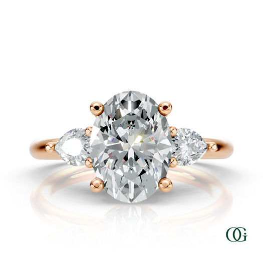 R | A rose gold three-stone engagement ring featuring a large oval-cut center diamond flanked by two marquise-cut side diamonds.
