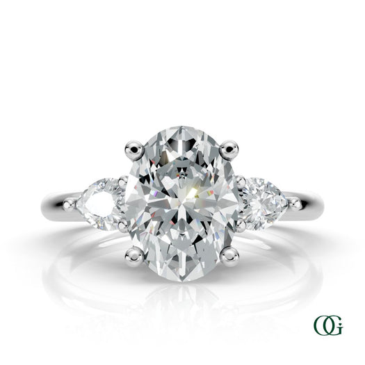 W | A white gold three-stone engagement ring featuring a large oval-cut center diamond flanked by two marquise-cut side diamonds.