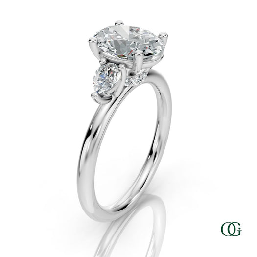 W | A white gold three-stone engagement ring featuring a large oval-cut center diamond flanked by two marquise-cut side diamonds.