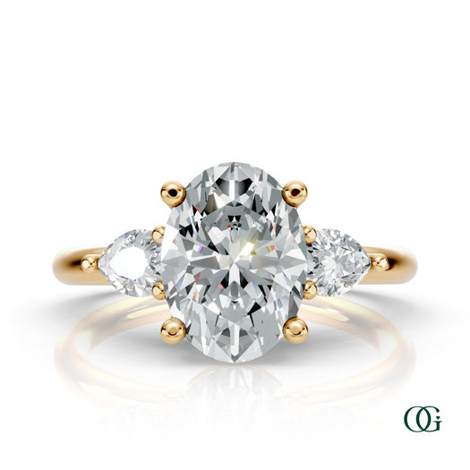 Y | A yellow gold three-stone engagement ring featuring a large oval-cut center diamond flanked by two marquise-cut side diamonds.