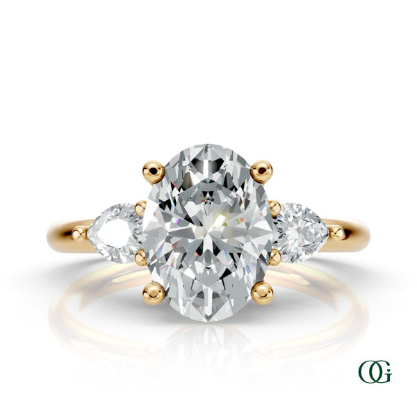 Y | A yellow gold three-stone engagement ring featuring a large oval-cut center diamond flanked by two marquise-cut side diamonds.