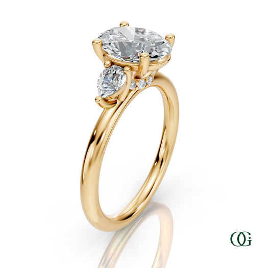 Y | A yellow gold three-stone engagement ring featuring a large oval-cut center diamond flanked by two marquise-cut side diamonds.