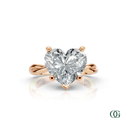 R | A heart-shaped diamond engagement ring in a rose gold setting with a twisted band, shown on a clean white background with a soft reflection.