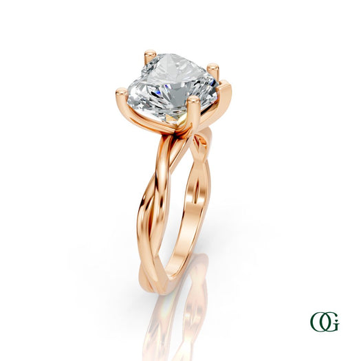 R | A heart-shaped diamond engagement ring in a rose gold setting with a twisted band, shown on a clean white background with a soft reflection.