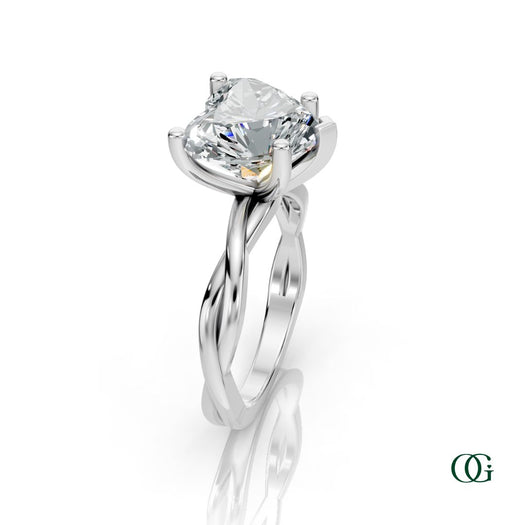 W | A heart-shaped diamond engagement ring in a white gold setting with a twisted band, shown on a clean white background with a soft reflection.