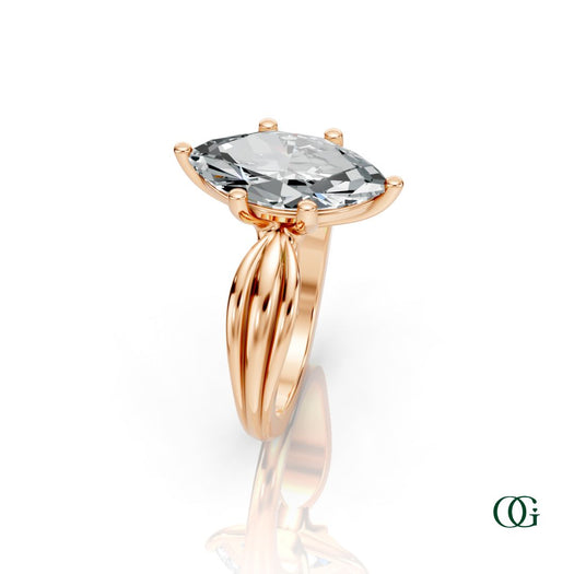 R | A rose gold ring featuring a large marquise-cut clear gemstone in a prong setting, with a sculptural, ribbed shank.