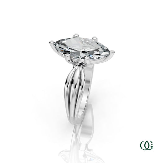W | A white gold ring featuring a large marquise-cut clear gemstone in a prong setting, with a sculptural, ribbed shank.