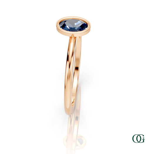 R| A rose gold ring featuring an oval sapphire birthstone for September