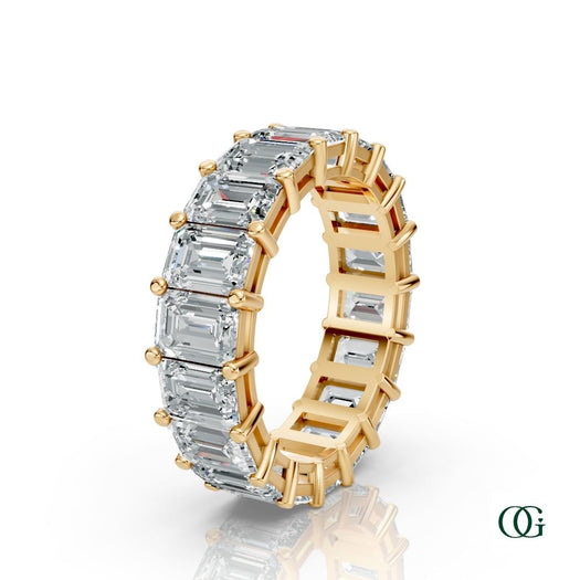 Y | A yellow gold eternity ring featuring a row of emerald-cut clear diamonds, set against a clean white background with a soft reflection.