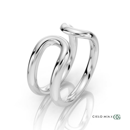 W | A polished white gold double-band ring with a sculptural, intertwined curved design, displayed on a clean white background with a soft reflection and the brand logo 'CIELO MIA x OG' in the bottom right corner.