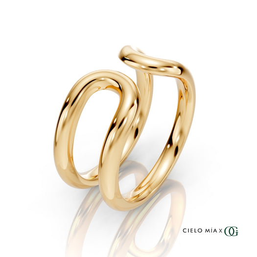 Y| A polished gold double-band ring with a sculptural, intertwined curved design, displayed on a clean white background with a soft reflection and the brand logo 'CIELO MIA x OG' in the bottom right corner.