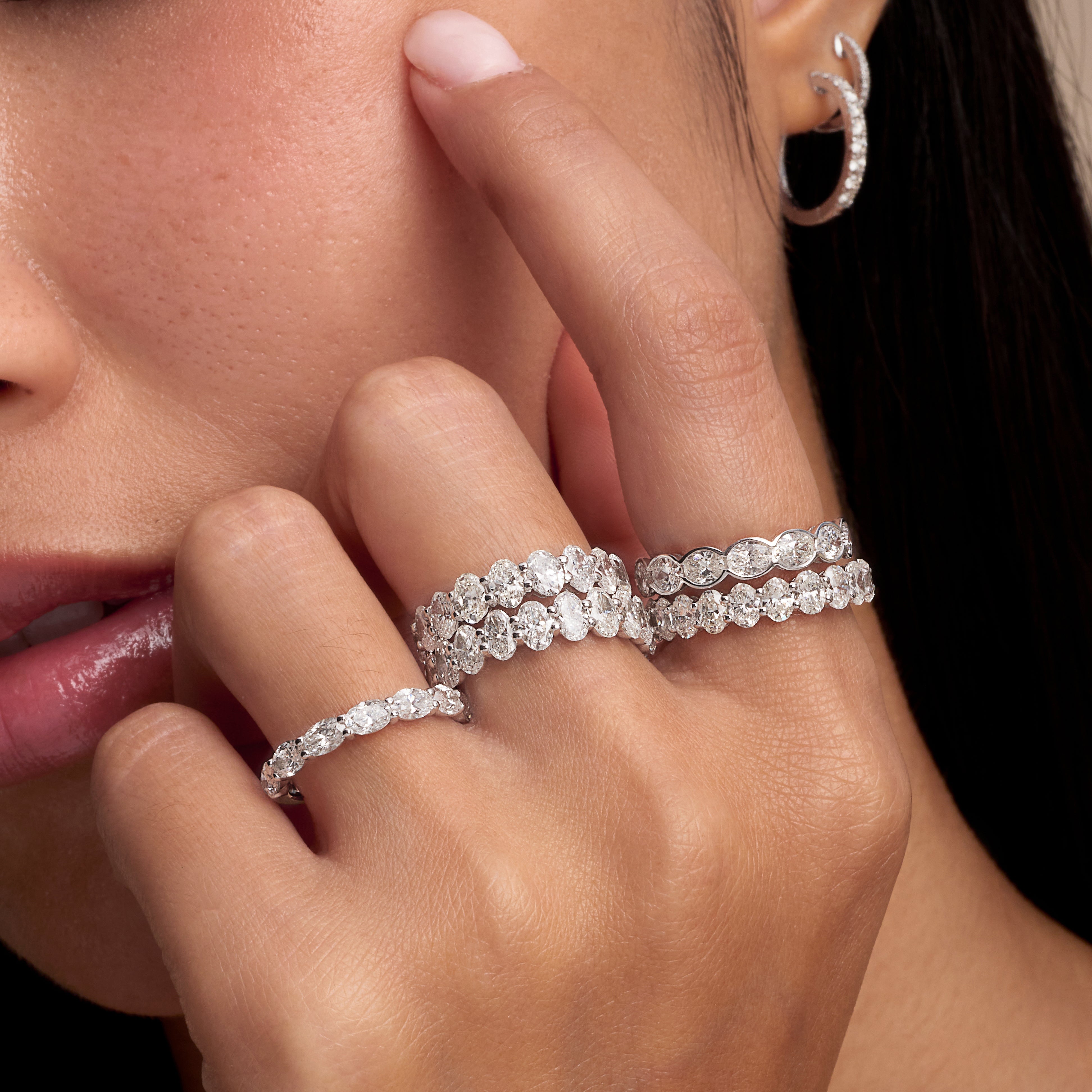 Close-up of a hand wearing two diamond rings with a blurred background