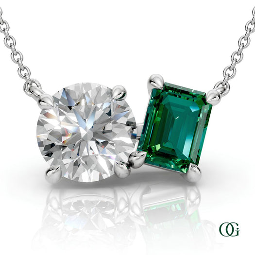 W | white gold necklace with two stones: a round diamond center stone and an  emerald-cut emerald side stone.