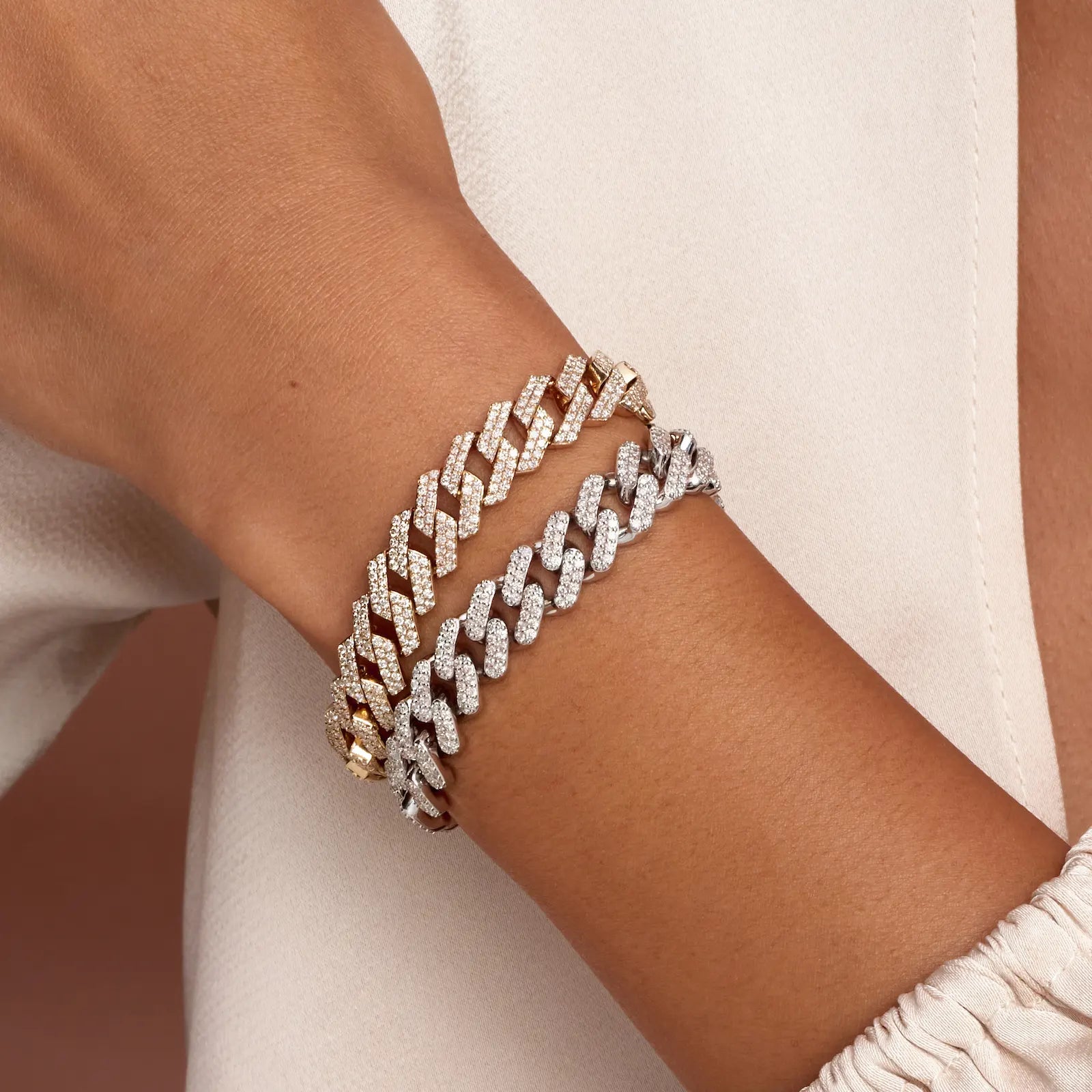 Two diamond-encrusted bracelets on a wrist with a neutral background