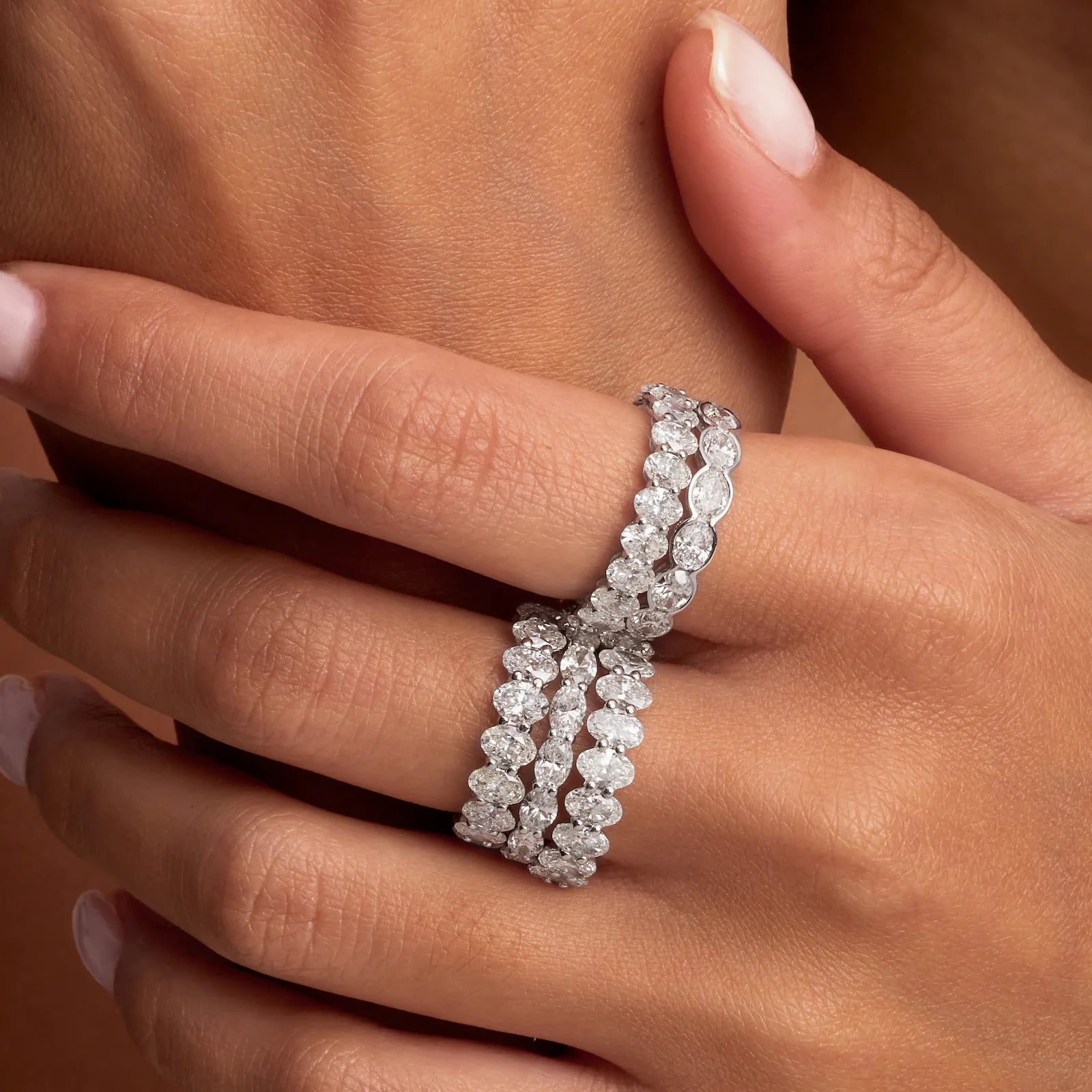 Close-up of a hand wearing a diamond bracelet on a neutral background